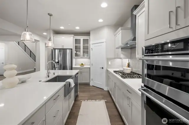 The kitchen is a showstopper, featuring gorgeous quartz countertops, stainless steel appliances, a spacious open island, gas cooktop, charming coffee bar nook, classic white shaker cabinets, and a timeless subway tile backsplash.