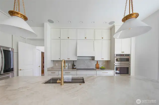 Quartzite counters, an expansive island, and custom pendant lighting add to the beauty and elegance of this newly remodeled kitchen.