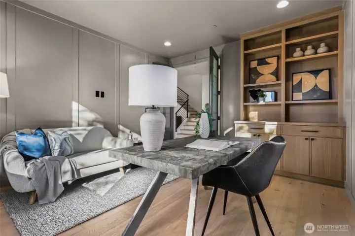 French doors open to a nice size office. Wide-plank engineered white oak hardwood flooring, and rift sawn oak furniture-style built-in cabinets, drawers, and open shelving. Two ceiling speakers with a volume control.