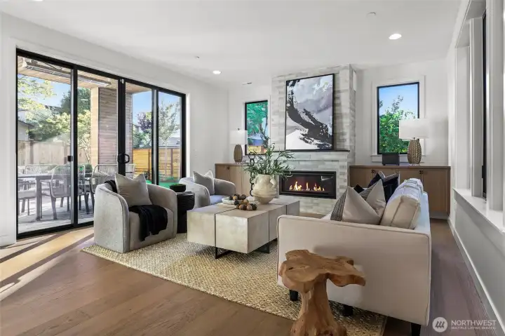 Spacious family room with double hanging cabinetry, linear gas fireplace with floor-to-ceiling tile surround and leathered granite mantle. There's a recessed outlet for a flat screen above the fireplace that has TV, cable, and network connection. Cabinets conceal A/V components. This room is pre-wired for two-ceiling speakers. Two Sonos® Connect:Amp® units are included with the home and power the ten installed speakers. Double sliding glass doors with two fixed panels bring in a lot of light and allow easy indoor/outdoor flow.