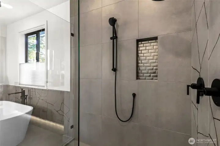 Tile set accent shampoo niche, two shower heads and large step-in shower with frameless glass doors.
