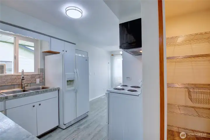 Easy flow kitchen with view of lighted walk-in pantry