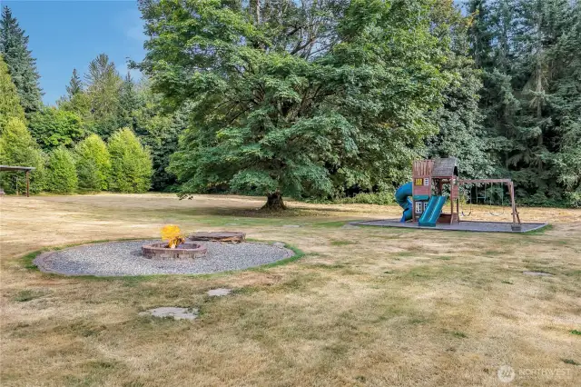 Parklike grounds with a play structure & fire pit.