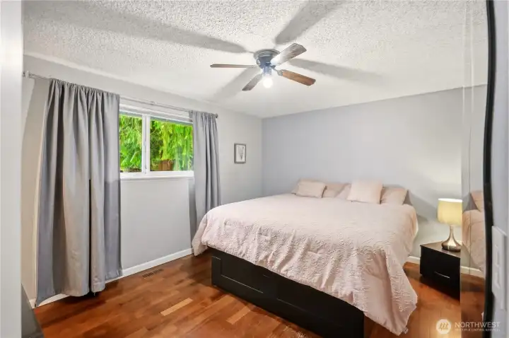 Primary bedroom with large windows overlooking the greenery.