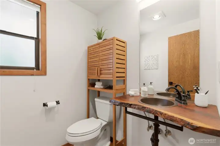 This powder room is on the main floor of the home. Notice the black walnut countertop with a live edge, a lovely feature of this guest bath.