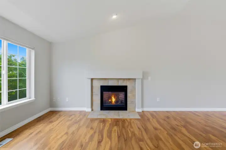 Relax in the inviting living room featuring beautiful wood-look flooring, abundant natural light, and a cozy fireplace that serves as the perfect focal point for gathering with family and friends Relax in the inviting living room featuring beautiful wood-look flooring, abundant natural light, and a cozy fireplace that serves as the perfect focal point for gathering with family and friends