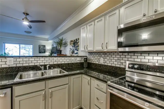 Kitchen features granite counters and subway tile backsplash