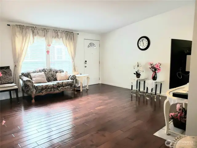 Another Spectacular View of the Living Room Showing Hard Wood Flooring, Newer Paint and Tiled Wood  Fireplace Looking at the Front Entry Door.