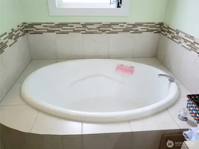A Close up View of the 5 Piece Primary Master Bathroom Showing Tile Soaking Tub Counter Top, Tile Floor, and Tile Tub Surround.
