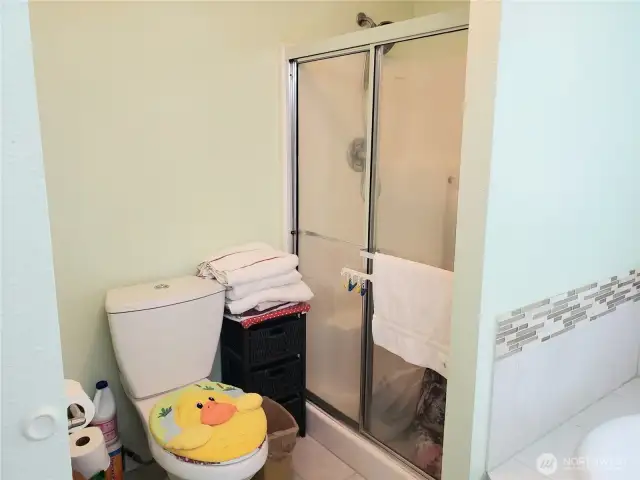 A Close up View of the 5 Piece Primary Master Bathroom Showing Tile Flooring, Newer Toilet, and Walk In Shower.