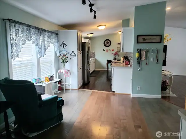 A View of the Huge Walk Through Kitchen with Tile Back Splash, White Cabinets, Stainless Appliances, Newer Paint and Hard Wood Flooring Looking from the Spacious Dining Room.