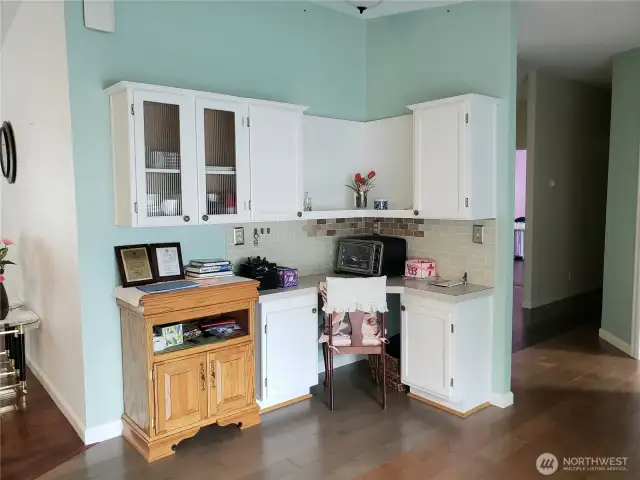 A Built In China Hutch In the Dining Room Area with White Cabinets, Tile Back Splash and  Hard Wood Flooring to Match the Kitchen.