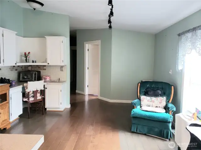 Another View of the Spacious Dining Room form The Kitchen Showing the Built In China Hutch In the Dining Room Area with White Cabinets, Tile Back Splash and Hard Wood Flooring to Match the Kitchen.