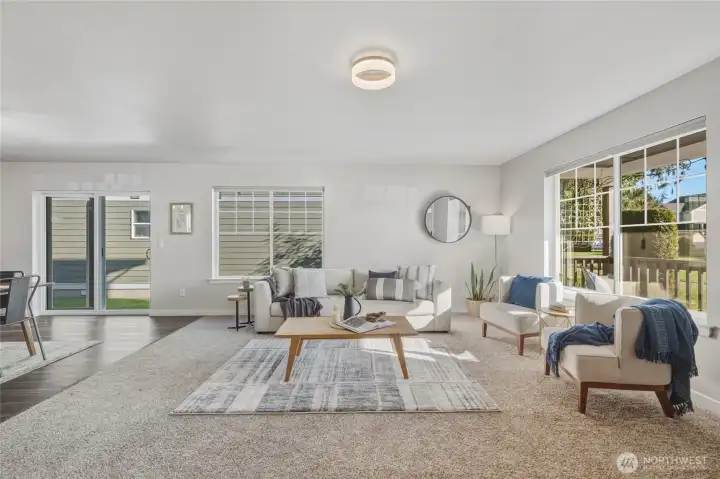 The spacious living room offers large windows on two sides for all-day sunlight, cozy carpet, and easy flow into the rest of the home.