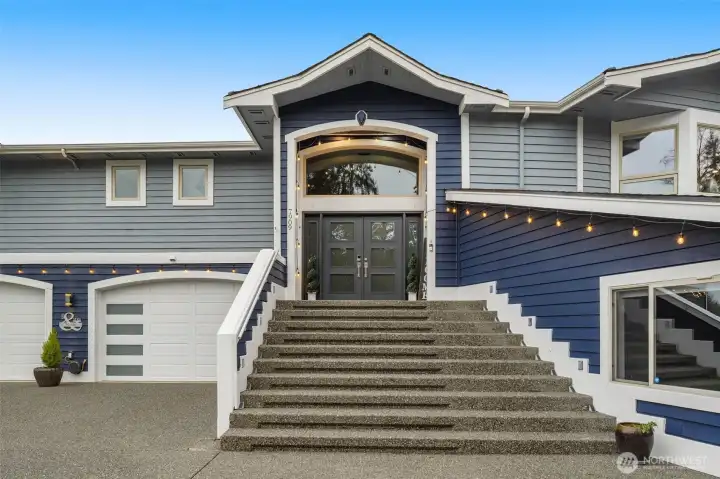 Grand front entry with elevated setting and welcoming staircase leading to the main level.