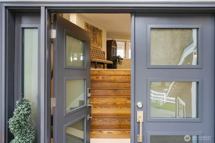 Inviting covered entry with double doors and warm wood staircase welcoming you inside.