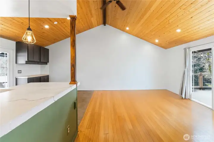 Large, airy living room with vaulted tongue-and-groove ceiling. Open concept to kitchen & dining area.