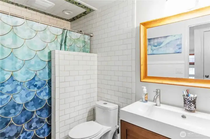 Guest bath with tile shower, floors & double faucet sink.