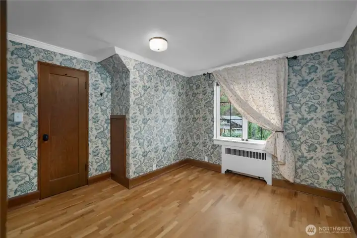 BR 2 - Vintage-inspired wallcovering, original trim, and hardwood floors give this bedroom a warm sense of character and charm.