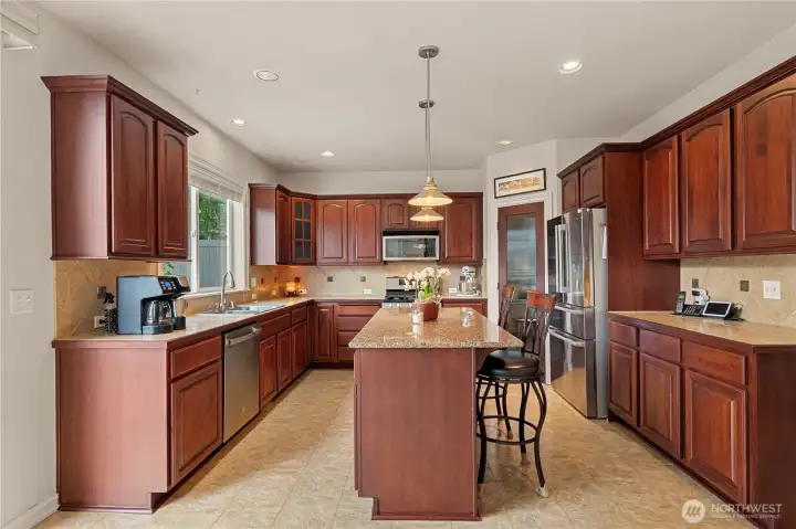 Kitchen is beautifully appointed with maple cabinetry, a center island, and slab granite countertops-perfect for everyday living and entertaining