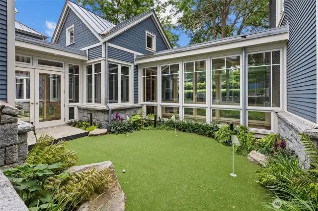 Putting green in courtyard surrounded by hallways and rooms in home