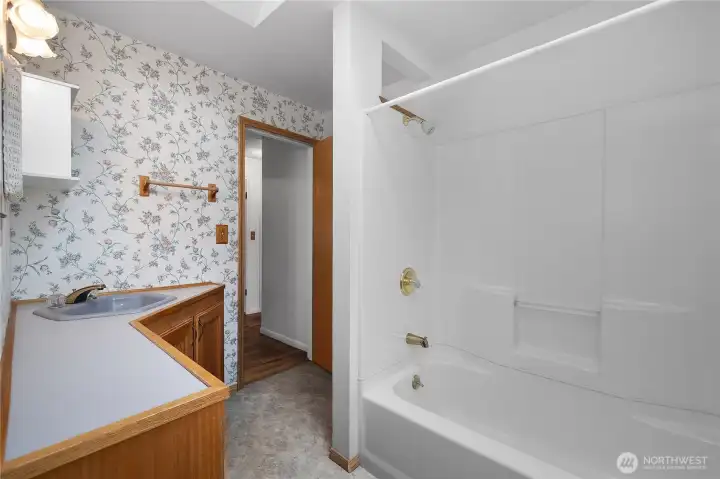 Main Level Full Bath - Clean full bathroom with tub/shower combination and natural light from the skylight.