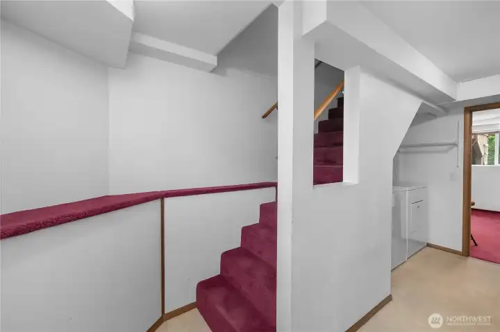 Stairs to the daylight basement level - Lower-level landing with laundry area and convenient access to additional finished spaces.