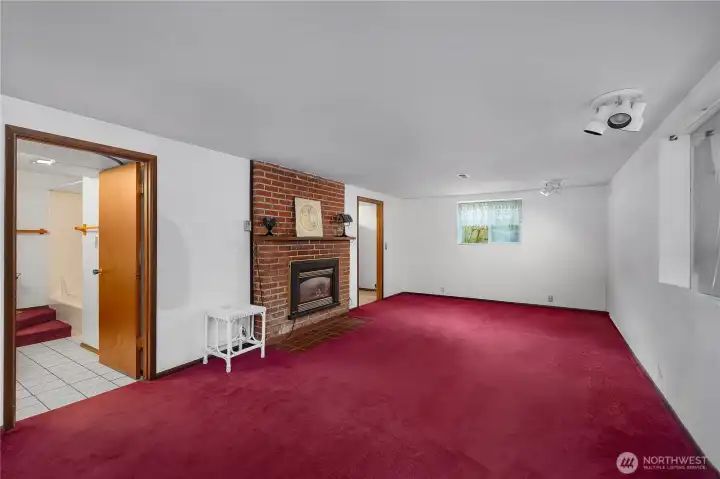 Large lower family room with fireplace, bright lighting, and flexible use potential.