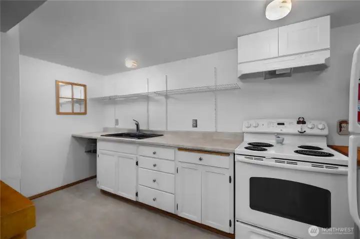 Lower-level kitchenette with sink, range, and generous countertop workspace.