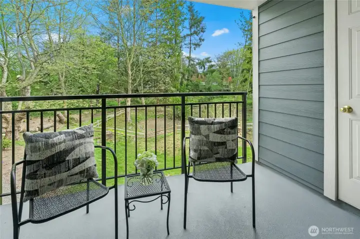 Covered balcony with seating and views of surrounding greenery.
