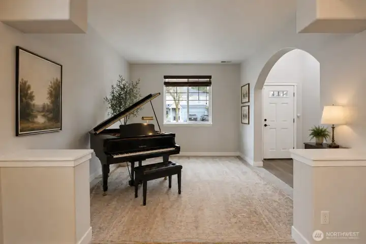 A bright, multi-purpose flex space with soaring ceilings, fresh paint, new carpet and abundant natural light. Elegantly staged with a beautiful Yamaha grand piano, this room is ideal for music, reading, working from home, or creative pursuits. Neutral palette, arched entryways, and stylish finishes make it easy to envision as a formal living room, office, or playroom — truly a versatile bonus space that adds tremendous value.