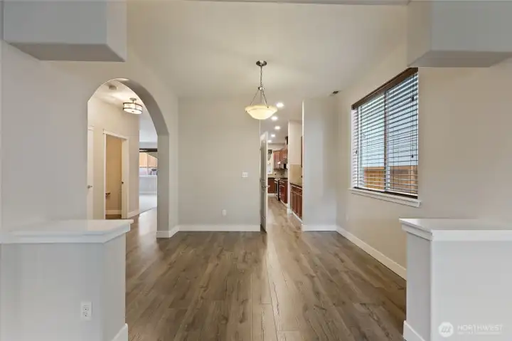 Beautifully framed by arched entryways and gleaming laminate flooring, this dining area offers neutral finishes, creating a bright, timeless space ideal for both intimate dinners and larger gatherings.