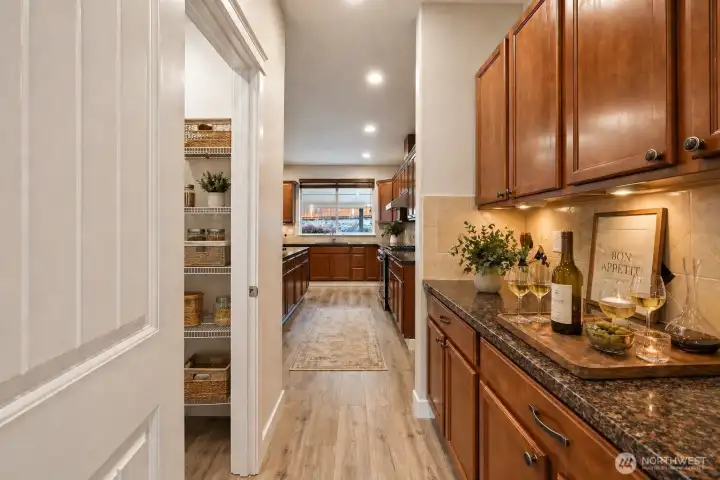 A spacious and highly functional butler’s pantry conveniently located between the dining room and kitchen with extensive cabinetry, prep counter, and adjacent walk-in pantry for added storage. Thoughtfully designed for both everyday convenience and effortless entertaining.