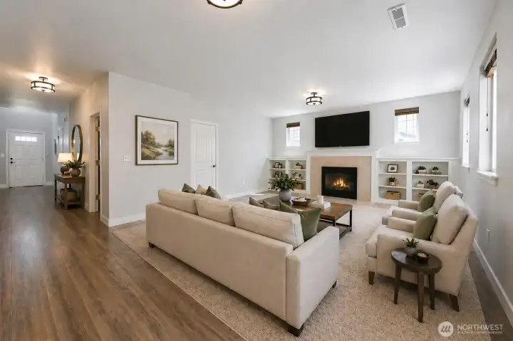 Expansive light-filled living room designed for both comfort and entertaining, featuring plush newer carpeting, elegant built-in shelving, and a cozy gas fireplace that creates the perfect gathering space. The open layout offers exceptional flexibility for large furniture arrangements, while oversized windows bring in abundant natural light. Seamlessly connected to the main living areas, this inviting space blends warmth, functionality, and everyday elegance.