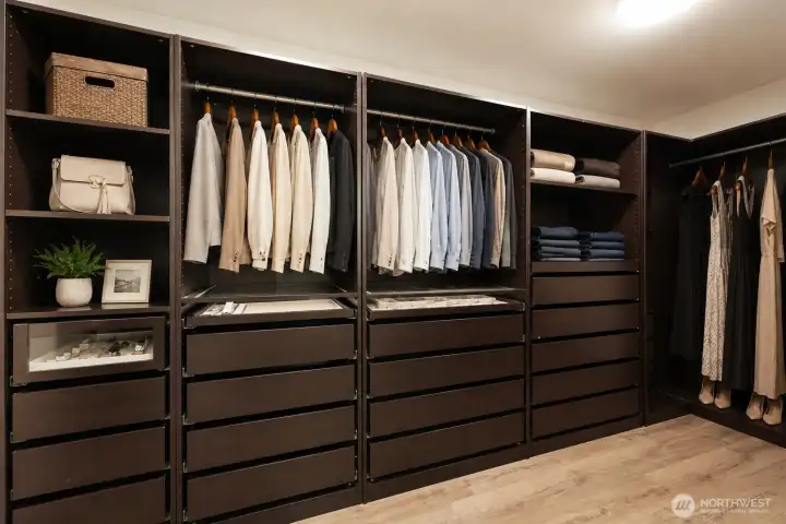 Expansive walk-in closet with a well-organized design high-end custom storage system, complete with rich cabinetry, multiple drawer banks, adjustable shelving, and ample hanging space. This boutique-style closet delivers both sophistication and exceptional organization.