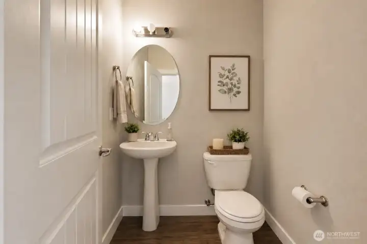 Elegant and thoughtfully styled, this inviting powder room blends modern simplicity with warm designer touches. Featuring rich large-plank laminate flooring, soft neutral tones, a sleek pedestal sink, and contemporary lighting, the space feels both refined and welcoming.