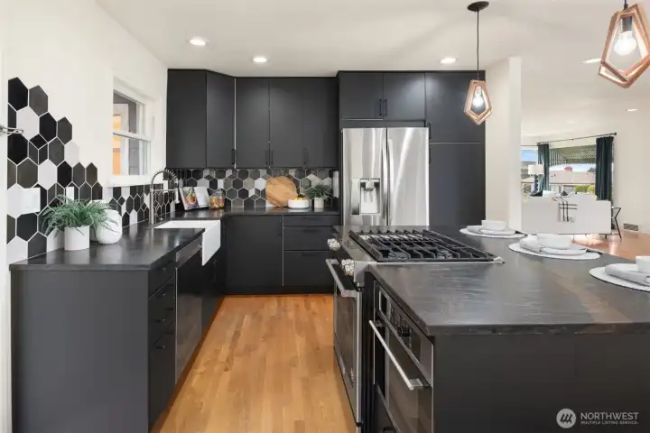 Beautifully appointed, the kitchen showcases rich Jatoba Brown leathered quartzite countertops paired with a custom tile backsplash, creating a timeless blend of warmth and modern sophistication.