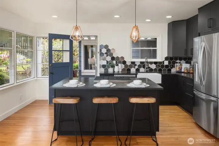 Hand-glazed tile, warm hardwood flooring, and seamless access to the inviting back patio create a kitchen designed for inspired cooking and effortless indoor-outdoor living.