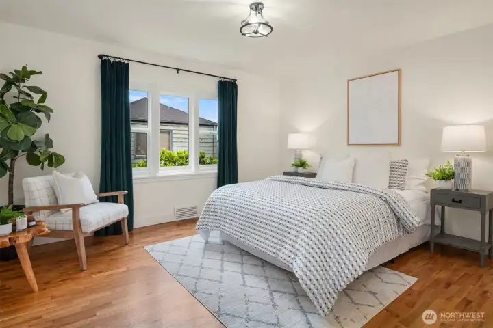 Rich hardwood flooring and abundant natural light create a warm, inviting bedroom designed as a peaceful retreat at the end of the day.
