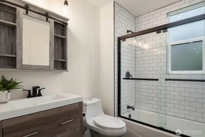 Thoughtfully reimagined with clean, contemporary finishes, the main-floor bathroom is highlighted by beautifully crafted tilework surrounding the shower and tub.