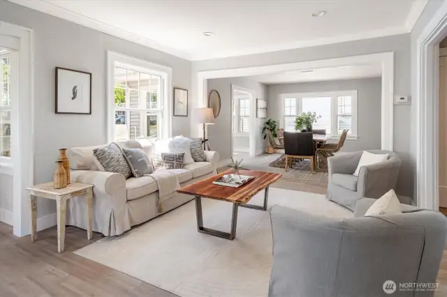 Living room with elegant floors, detailed millwork, and generous windows define a light-filled great room made for connection and entertaining.
