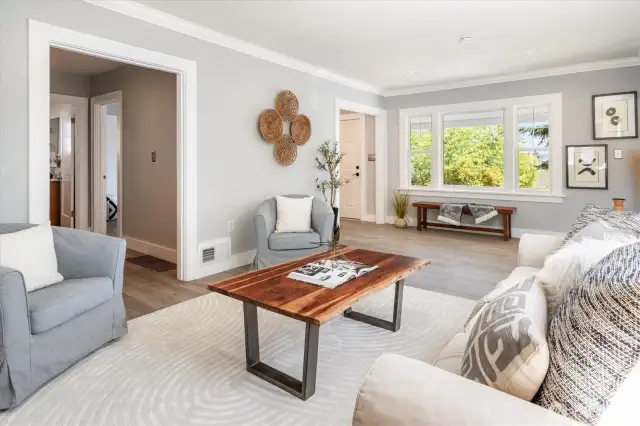 Living room with elegant floors, detailed millwork, and generous windows define a light-filled great room made for connection and entertaining.