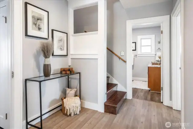 Airy hallway connects the bedroom, bathroom, and staircase leading upstairs
