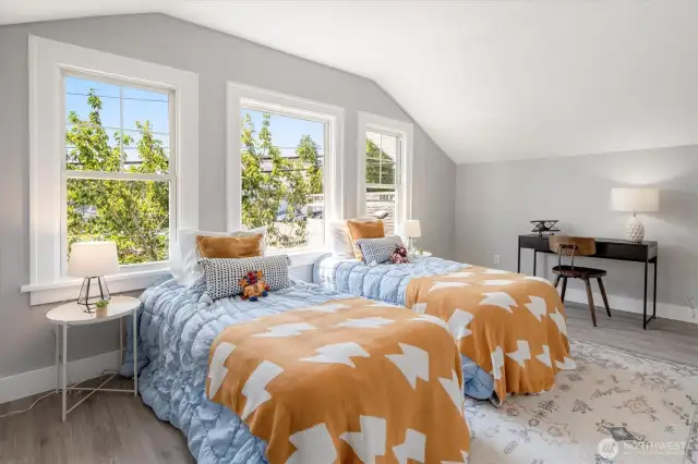 Large bedroom drenched in light offers room for sleep, play, and imagination at every stage