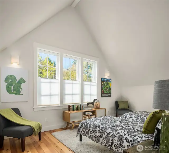 One of two light filled upstairs bedrooms under vaulted spaces. Solid wood floors grace all rooms in this home.