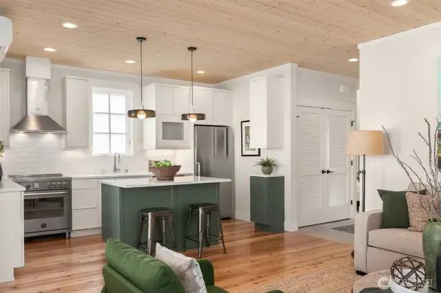 Custom cabinetry is painted a wam accent color on the kitchen island. Quartz counters grace the kitchen.