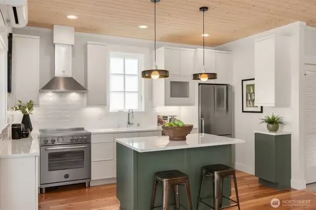The chef's kitchen features high performance Bertazzoni Induction cooking with 650 CFM range hood, under counter lights and playful pendants over the kitchen island.