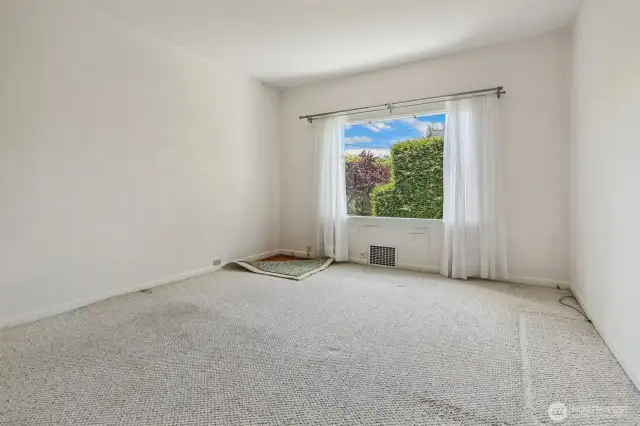 Primary bedroom is on the main floor.  It appears to have original Fir floors underneath the carpets.