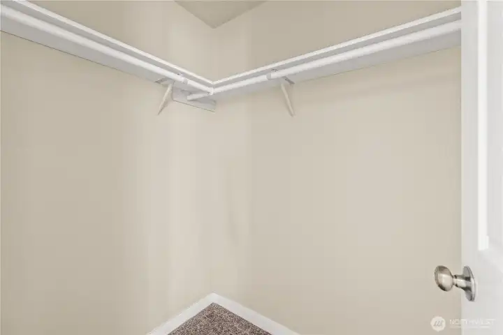Generous walk-in closet with built-in dual hanging rods and upper shelving, offering plenty of storage for clothing and accessories. Conveniently located inside the primary suite for easy organization and functionality.