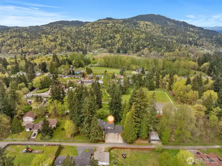 Aerial view with home location highlighted, nestled among mature trees with scenic surroundings in every direction.